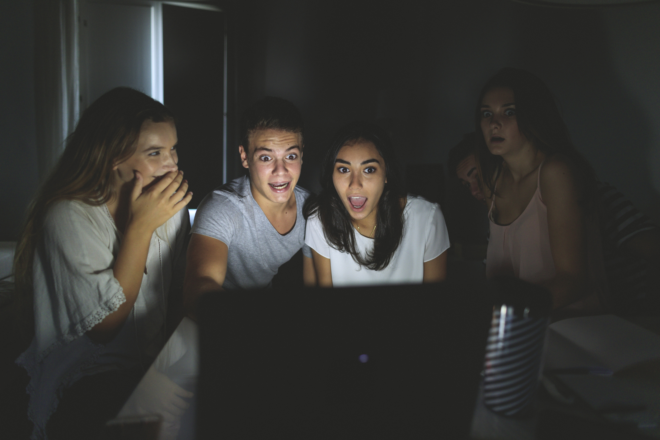 College students watching scary movie on laptop